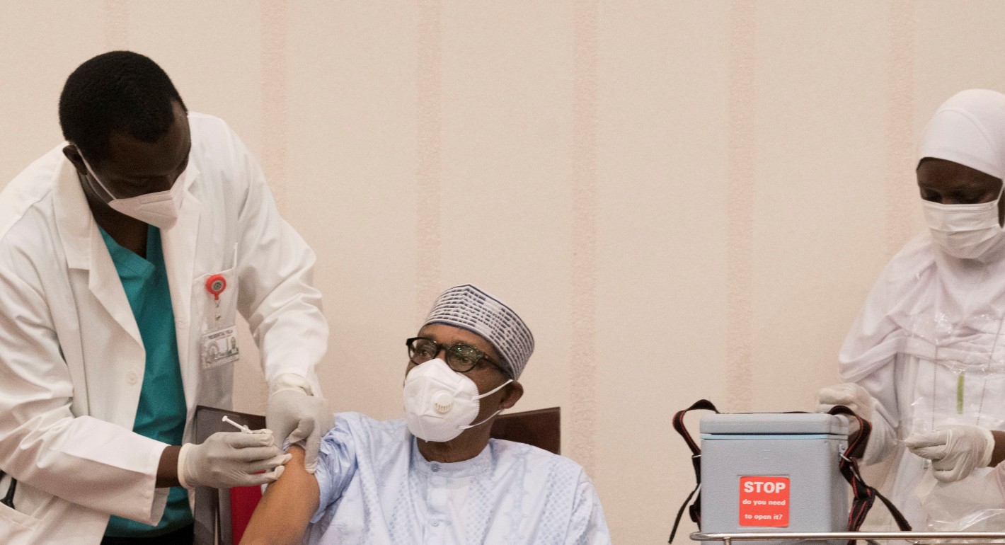 Nigeria President Muhammadu Buhari (C) receives his first dose of the Oxford/AstraZeneca vaccine